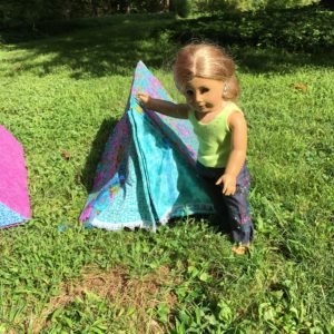 An American girl doll standing proud near her handmade tent!