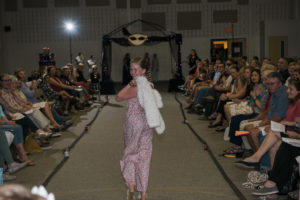 Eleven year old Fashion student walking down the runway in the jumper and white fur coat she designed and sewed.