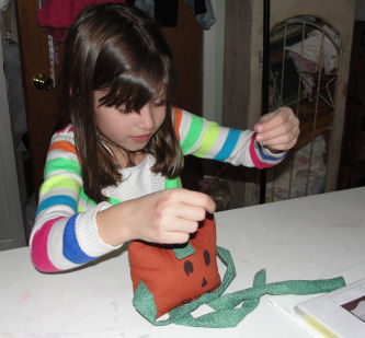 Morgan hand sewing top of pumpkin doll