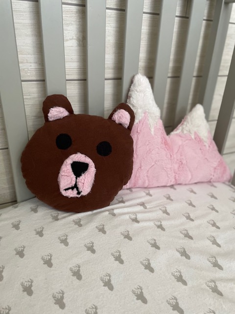 brown and pink teddy bear pillow and snow covered pink mountain pillow