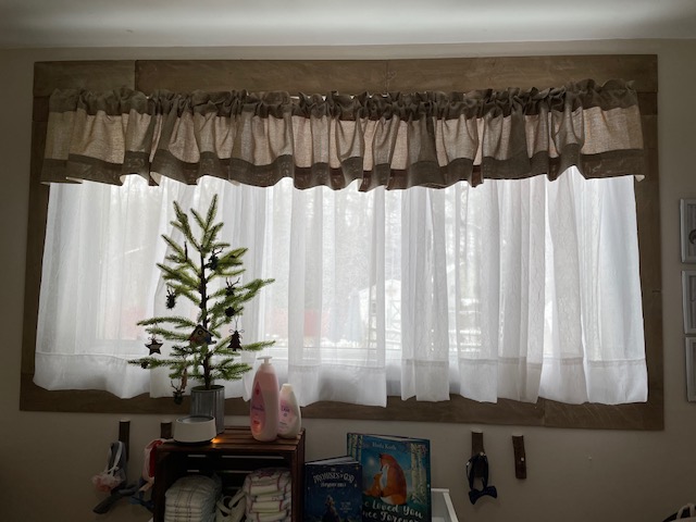 window with wood trim and brown curtains and little woodland tree