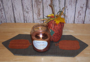 finished pumpkin appliqué table runner with spiced candle and pumkin sitting in middle