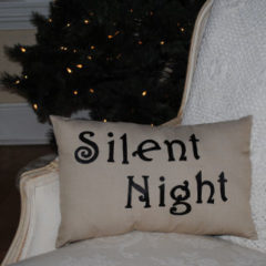 A tan pillow with iron on writing that says Silent Night
