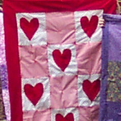 a quilt with red, pink, and white fabric and hearts